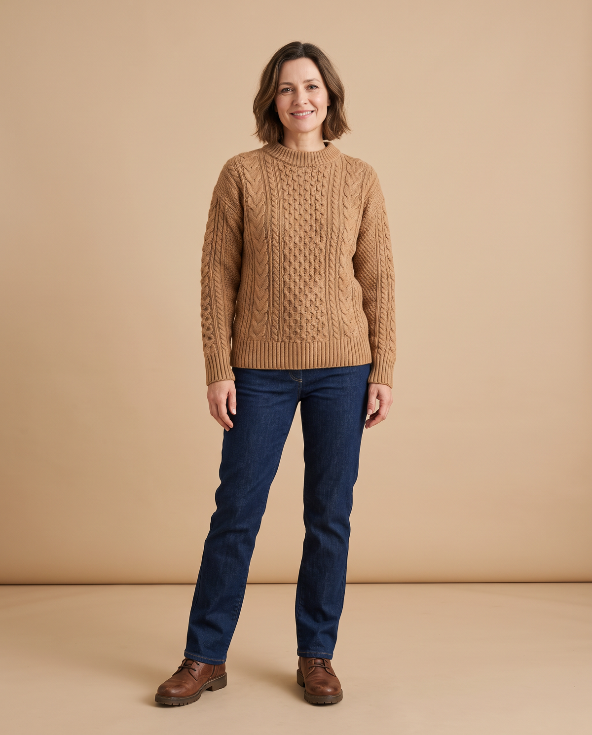 Damenpullover und Strickjacken – Frau im Camel-Strickpullover vor beigem Hintergrund